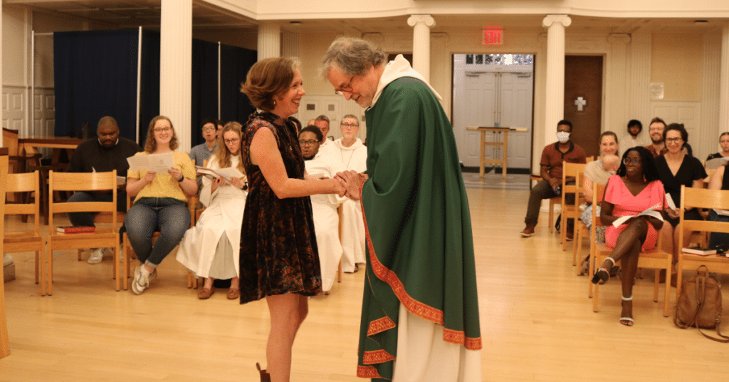 Whitney Kimball Coe in black dress shakes hand of priest at Yale