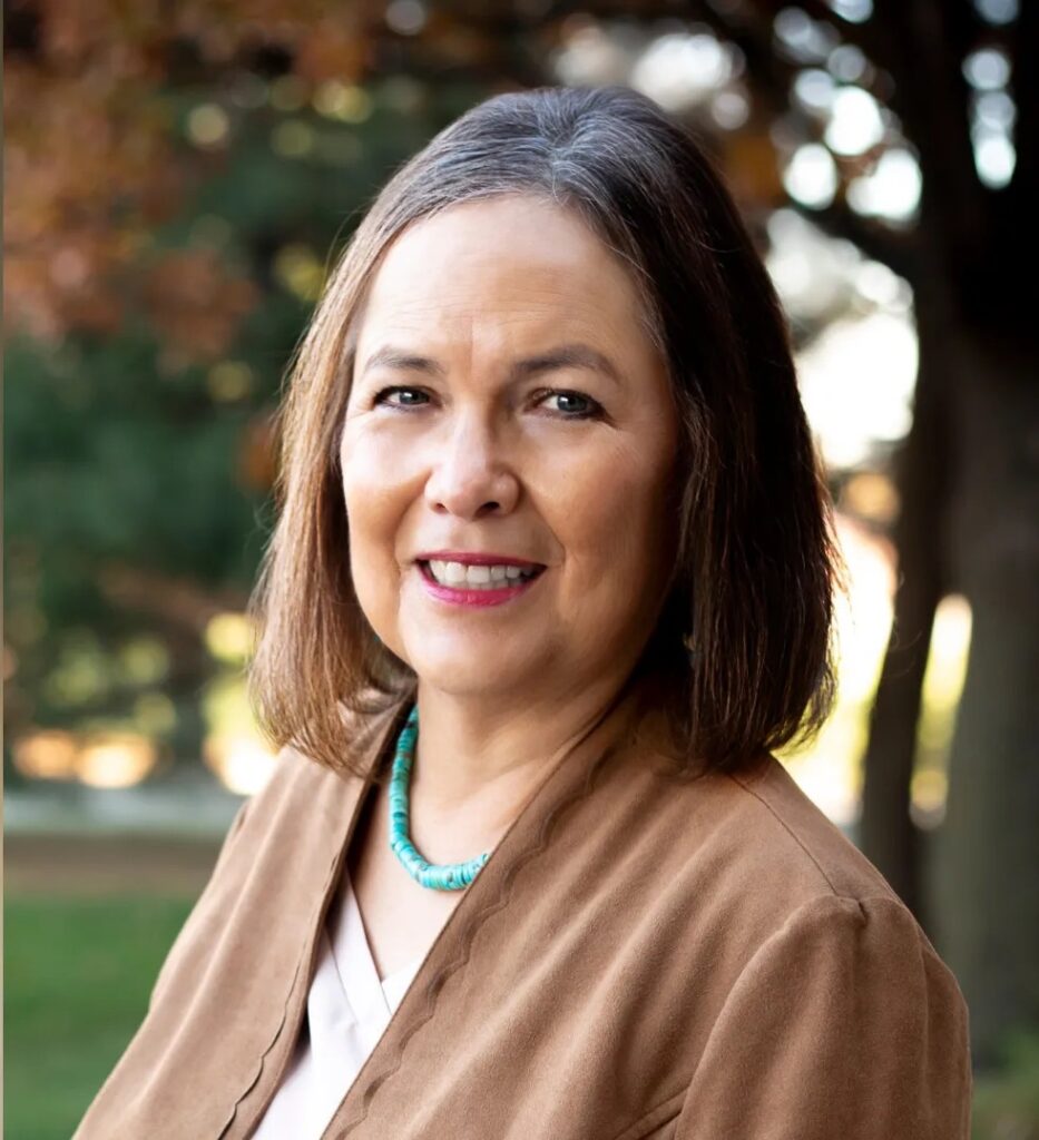 Shirley Sneve in brown jacket with turquoise necklace outdoors
